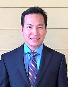 Hoang Le's professional headshot, wearing a blue suit jacket, baby blue shirt and purple tie.