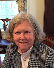 Susan's professional headshot wearing a grey suit jacket and white turtleneck sweater