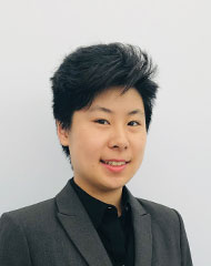 Melody's professional headshot wearing a grey suit jacket and black shirt